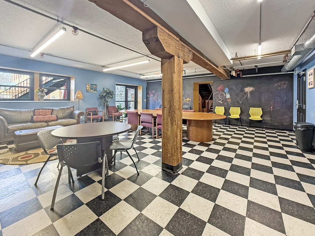 A black and white checkered floor in a room with a wooden pillar.
