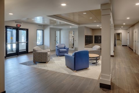 A spacious waiting area with blue chairs and a wooden floor.