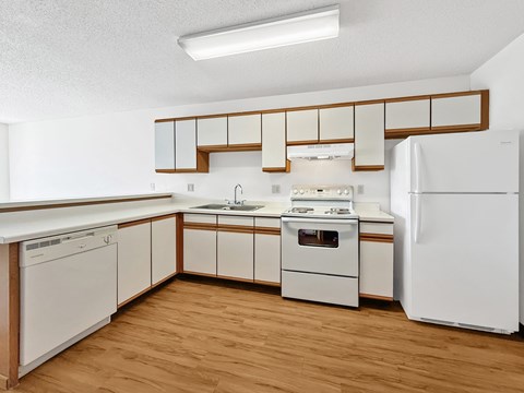 A kitchen with white appliances and wooden cabinets.