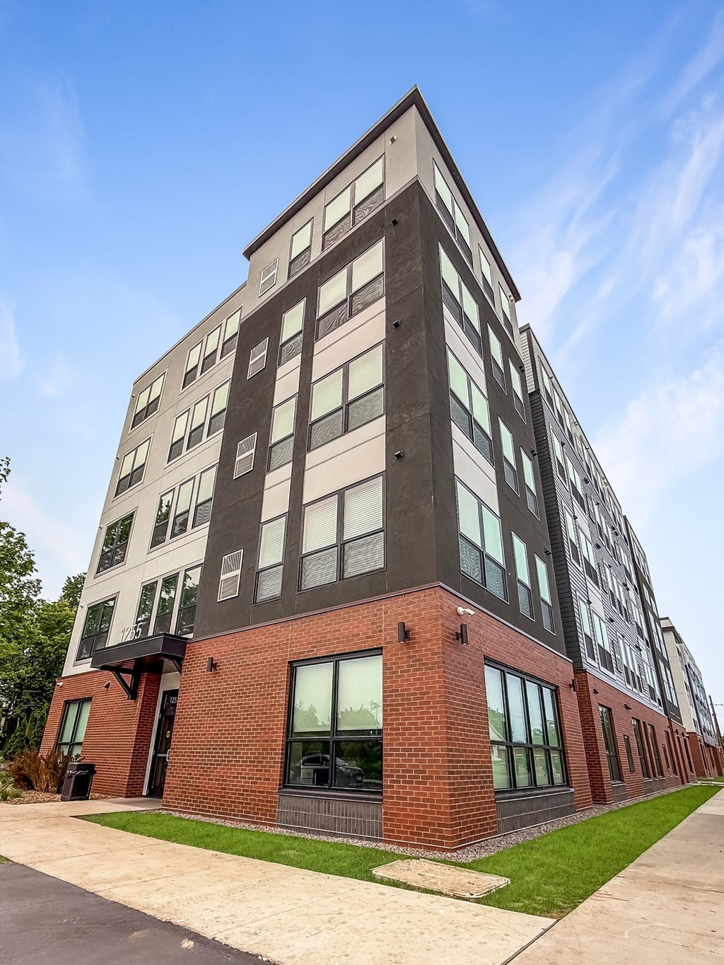 A modern multi-story building with a combination of brick and panel facades.
