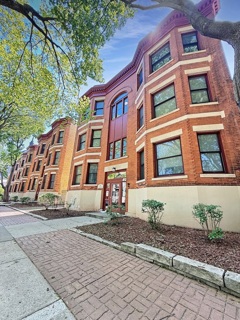 A red brick building with a tree in front.