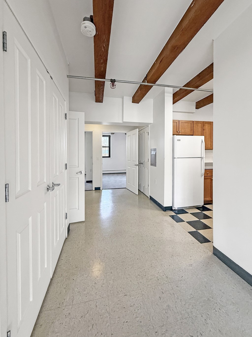 A long white hallway with a checkered floor.
