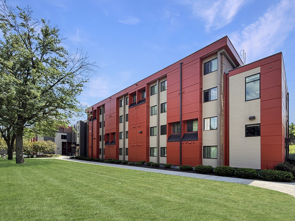 A red and beige building with a tree in front.