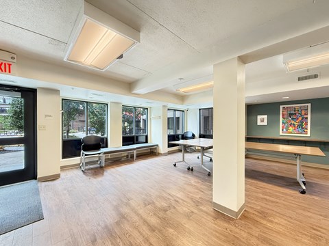 A room with a wooden floor, a white column, and a black chair.