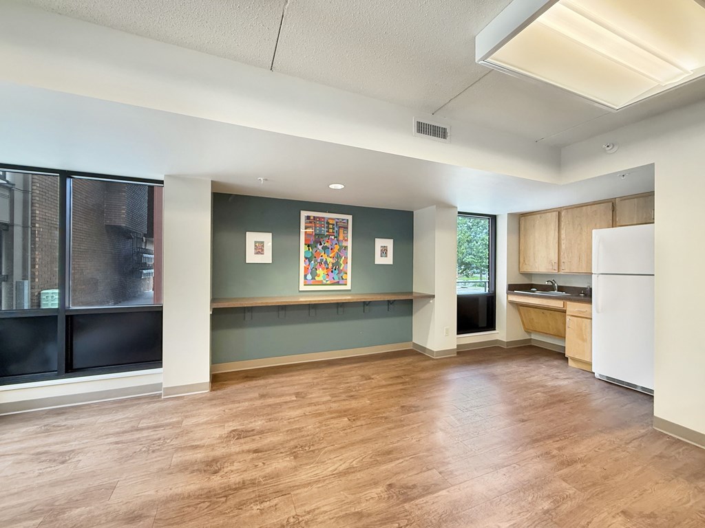 A kitchen area with a refrigerator, a counter, and a window.