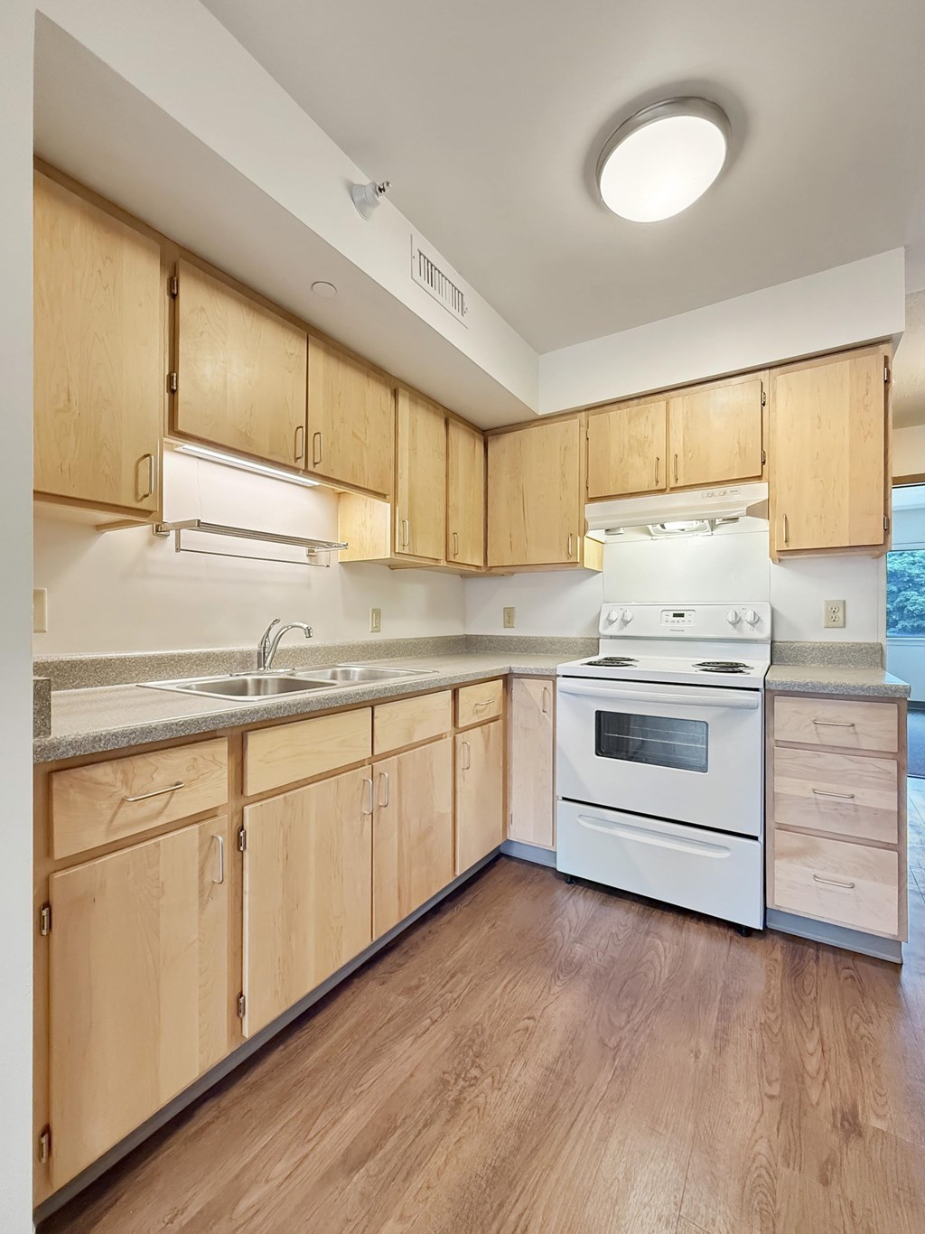 A kitchen with wooden cabinets and a white stove top oven.