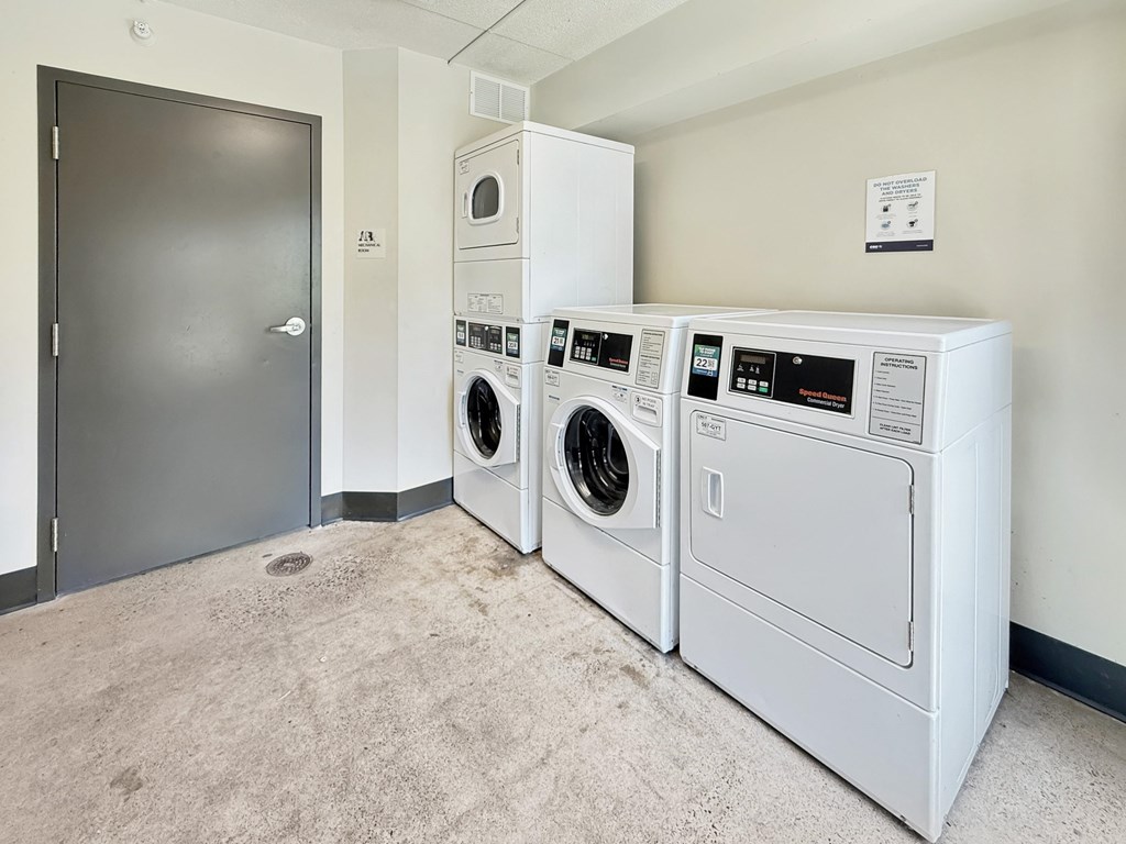 A stack of three front loading washing machines in a laundry room.