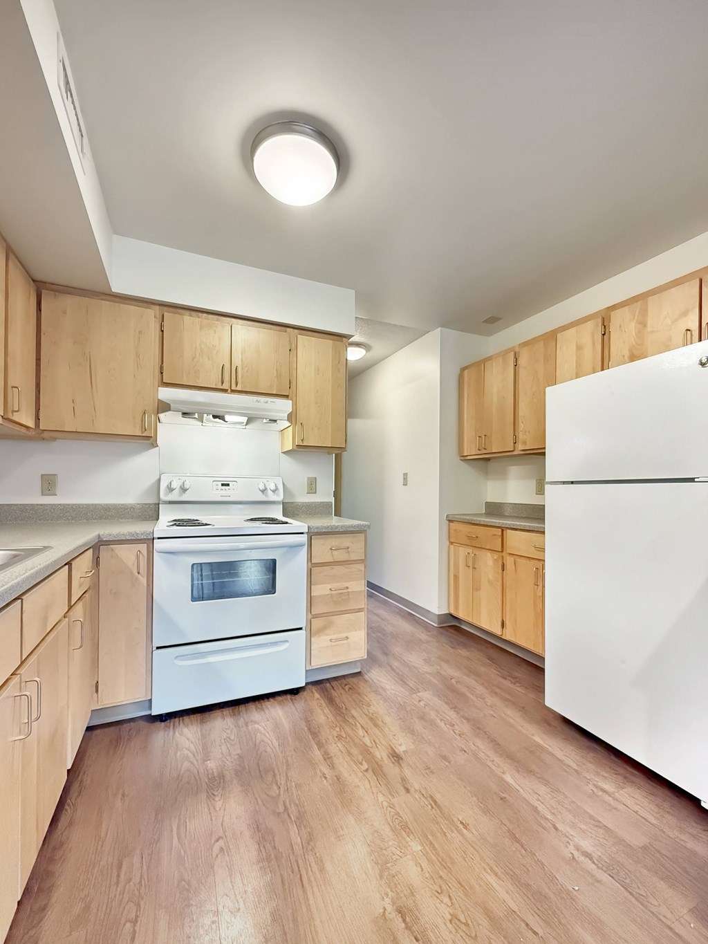 A kitchen with wooden cabinets and a white refrigerator.