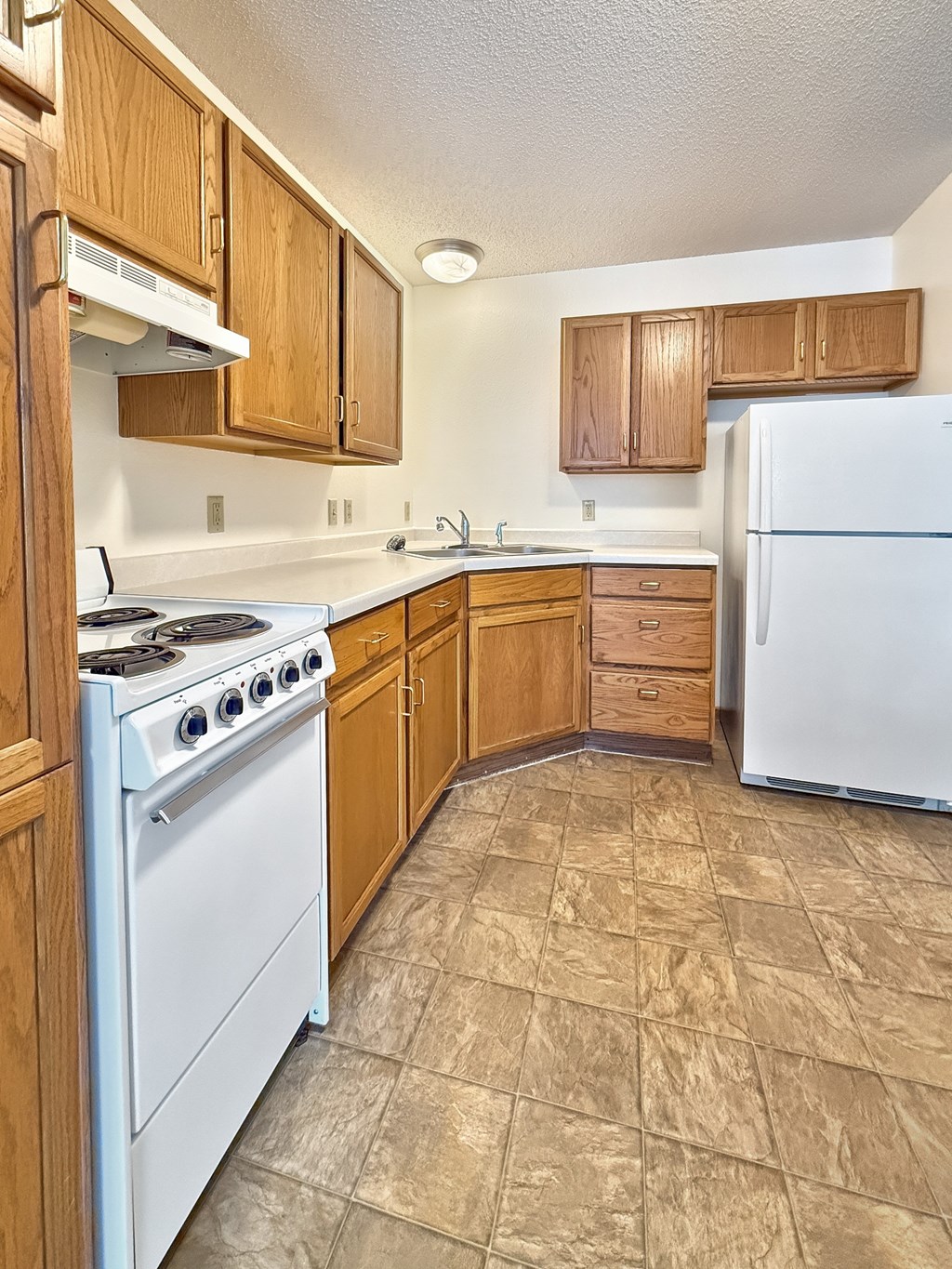 A kitchen with a white stove and white refrigerator.