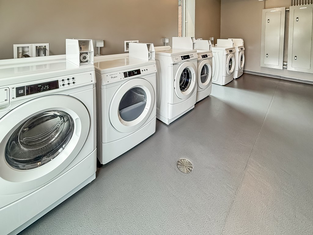 A row of white front load washing machines in a laundromat.