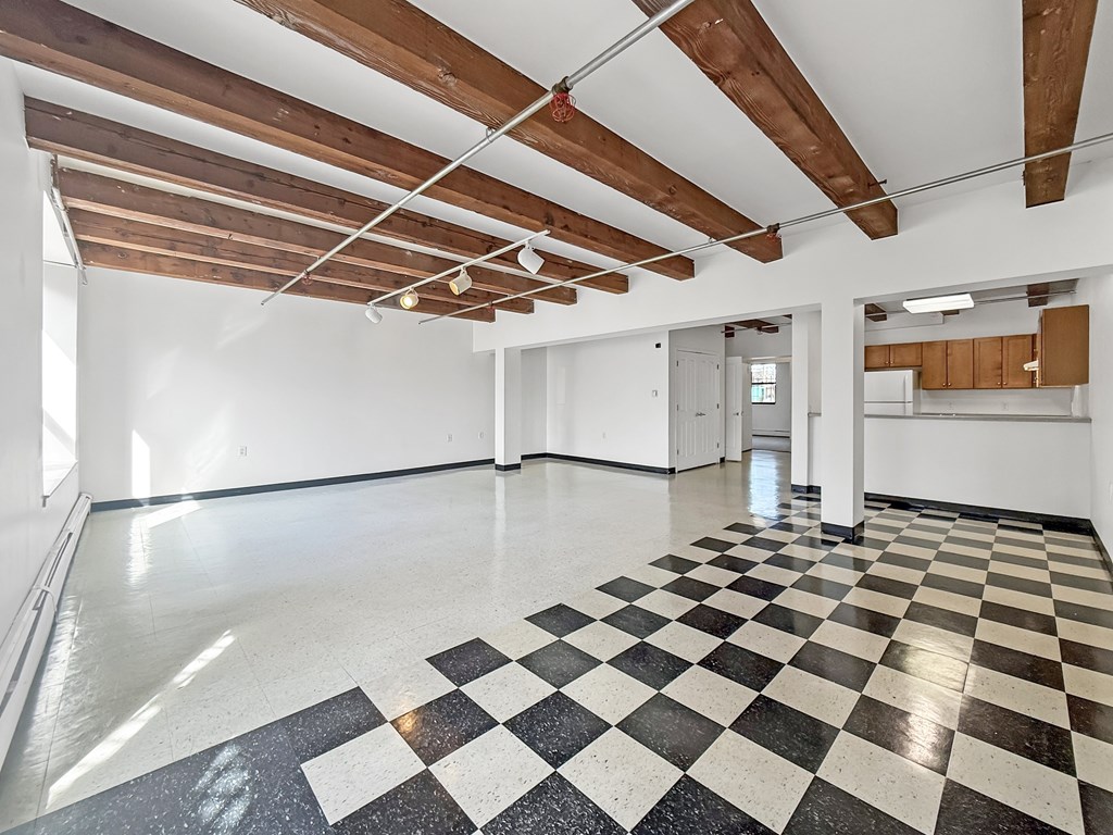 A large empty room with black and white checkered flooring and wooden beams on the ceiling.