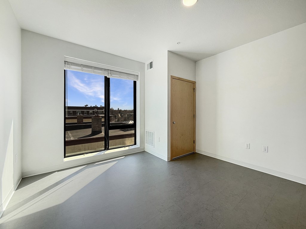 A room with a large window and a wooden door.