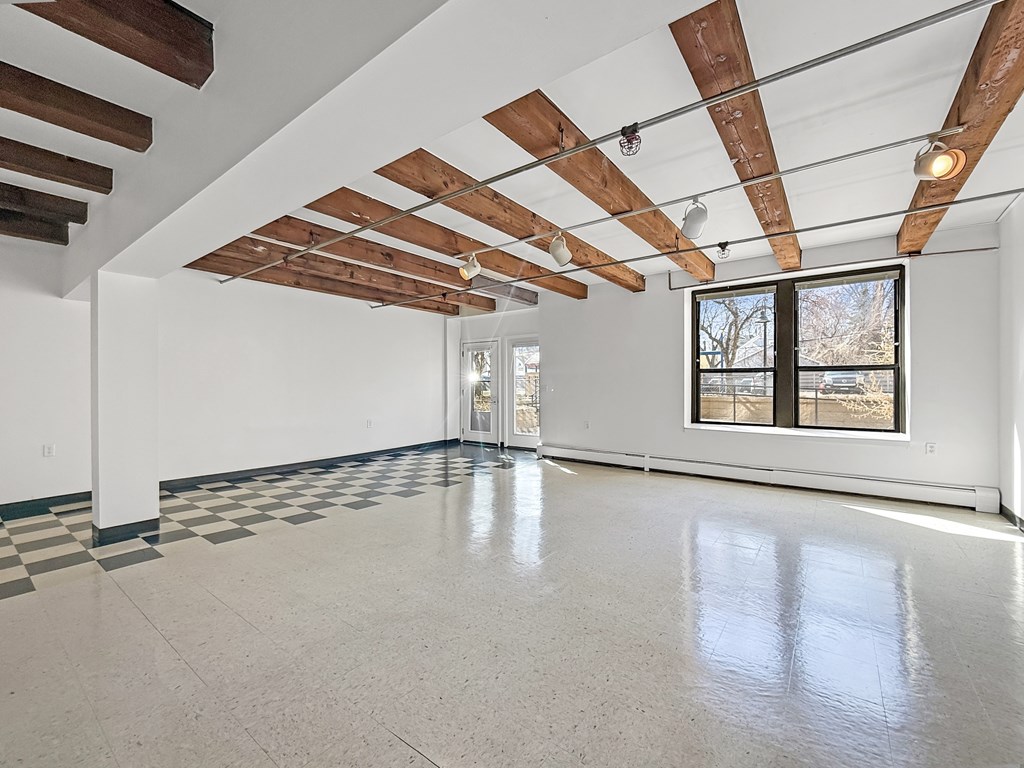 A spacious room with a checkered floor and wooden beams on the ceiling.