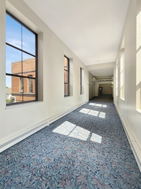 A long hallway with a blue carpet and white walls.