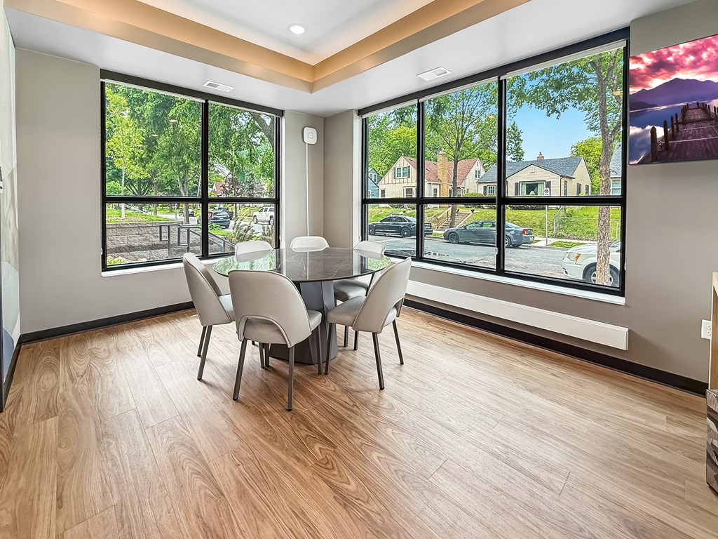 A dining room with a table and chairs with a view of the street outside.