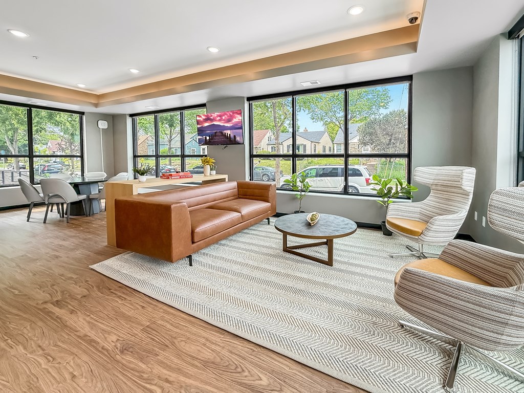 A living room with a brown leather couch and a grey chair.