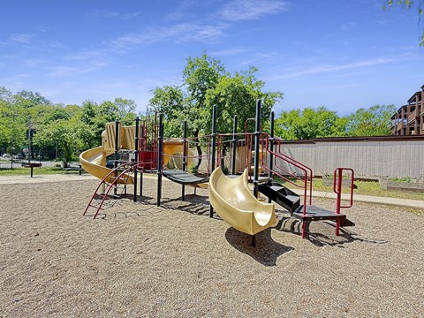 A playground with a yellow slide and red and black equipment.