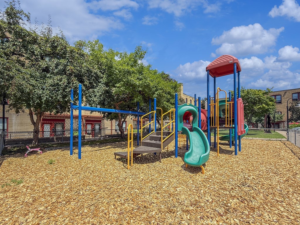 A playground with a red and blue slide and a green slide.