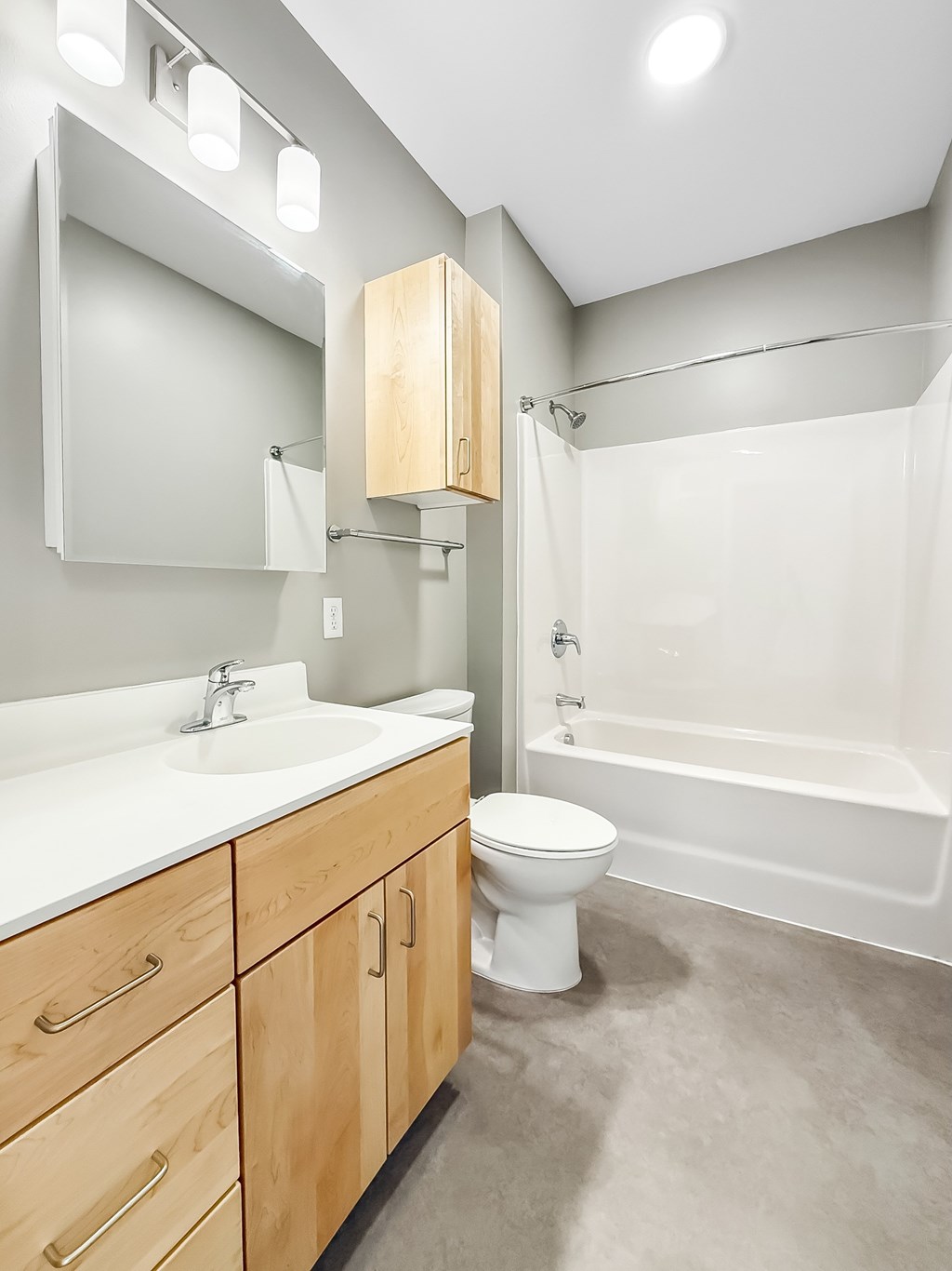 A white sink and toilet in a bathroom with wooden cabinets.