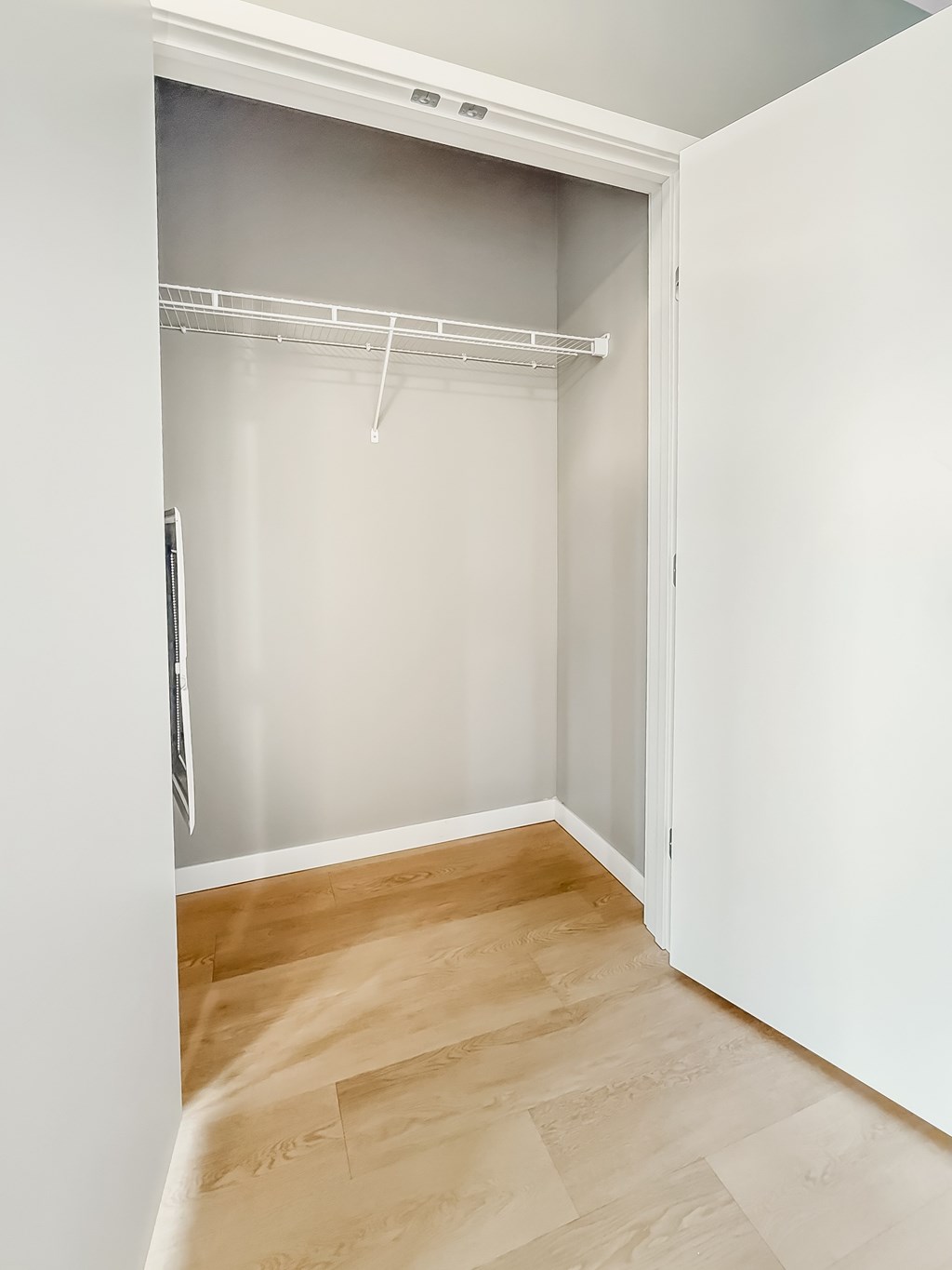 A white closet with a white door and a white shelf.