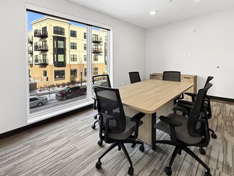 A conference room with a table and chairs and a view of a street outside.