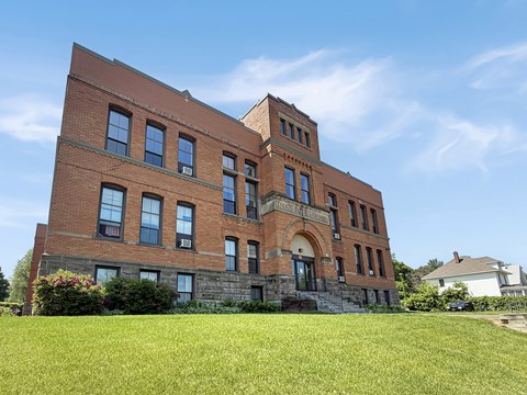 A red brick building with a tower and arched doorway.
