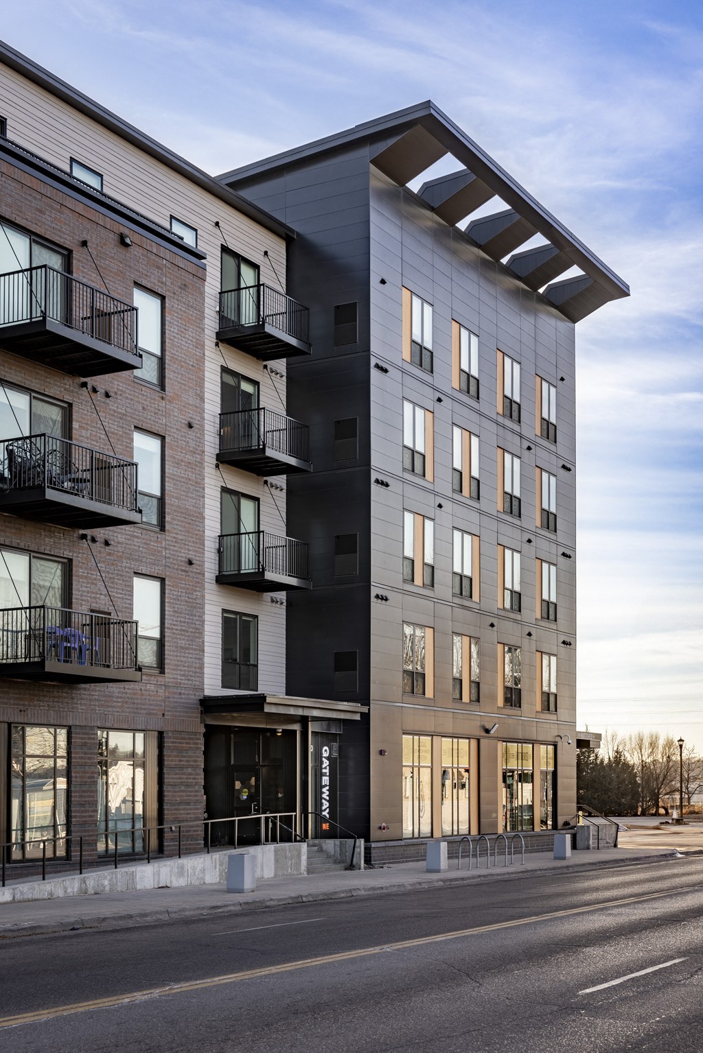 A modern apartment building with balconies on the second floor.