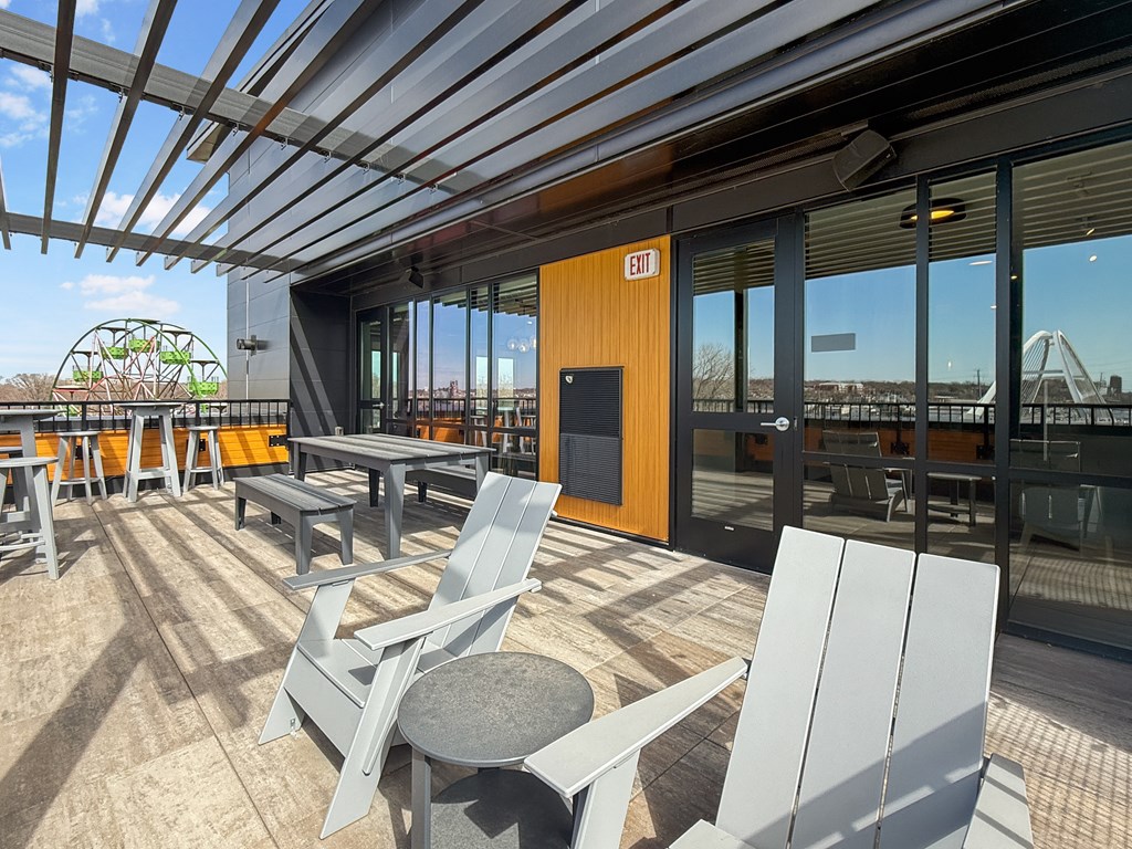 A patio with chairs and tables is covered by a roof.