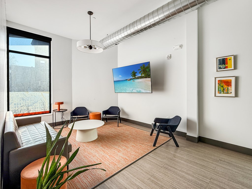 A living room with a television, chairs, and a plant.