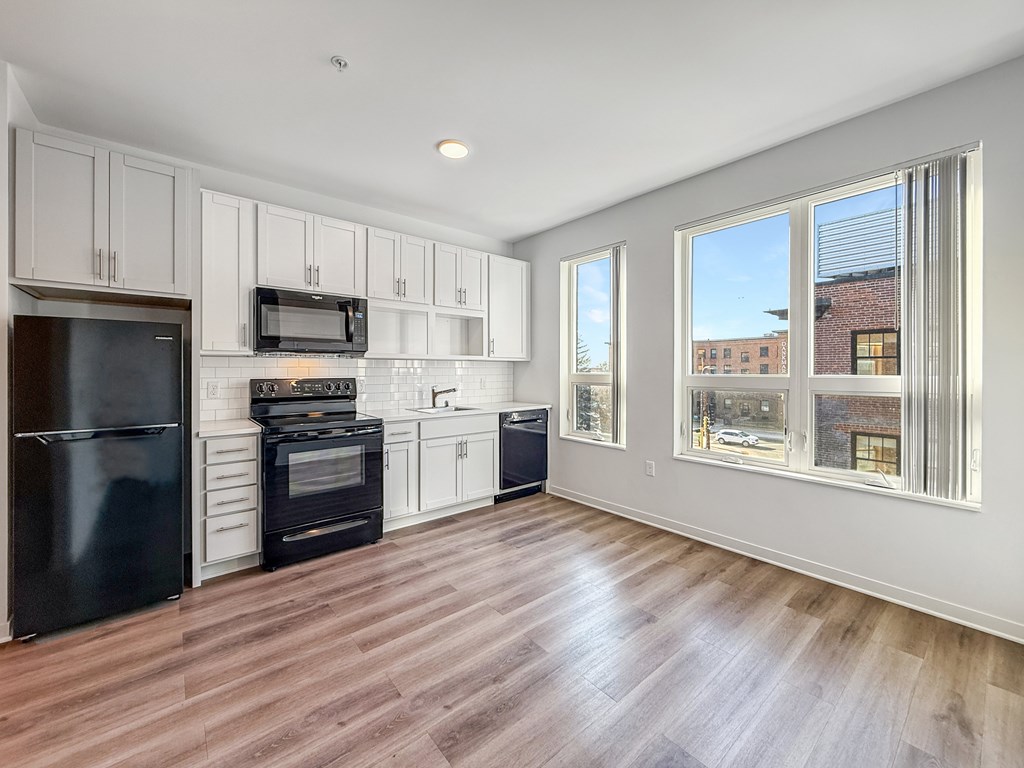 A kitchen with black appliances and white cabinets.