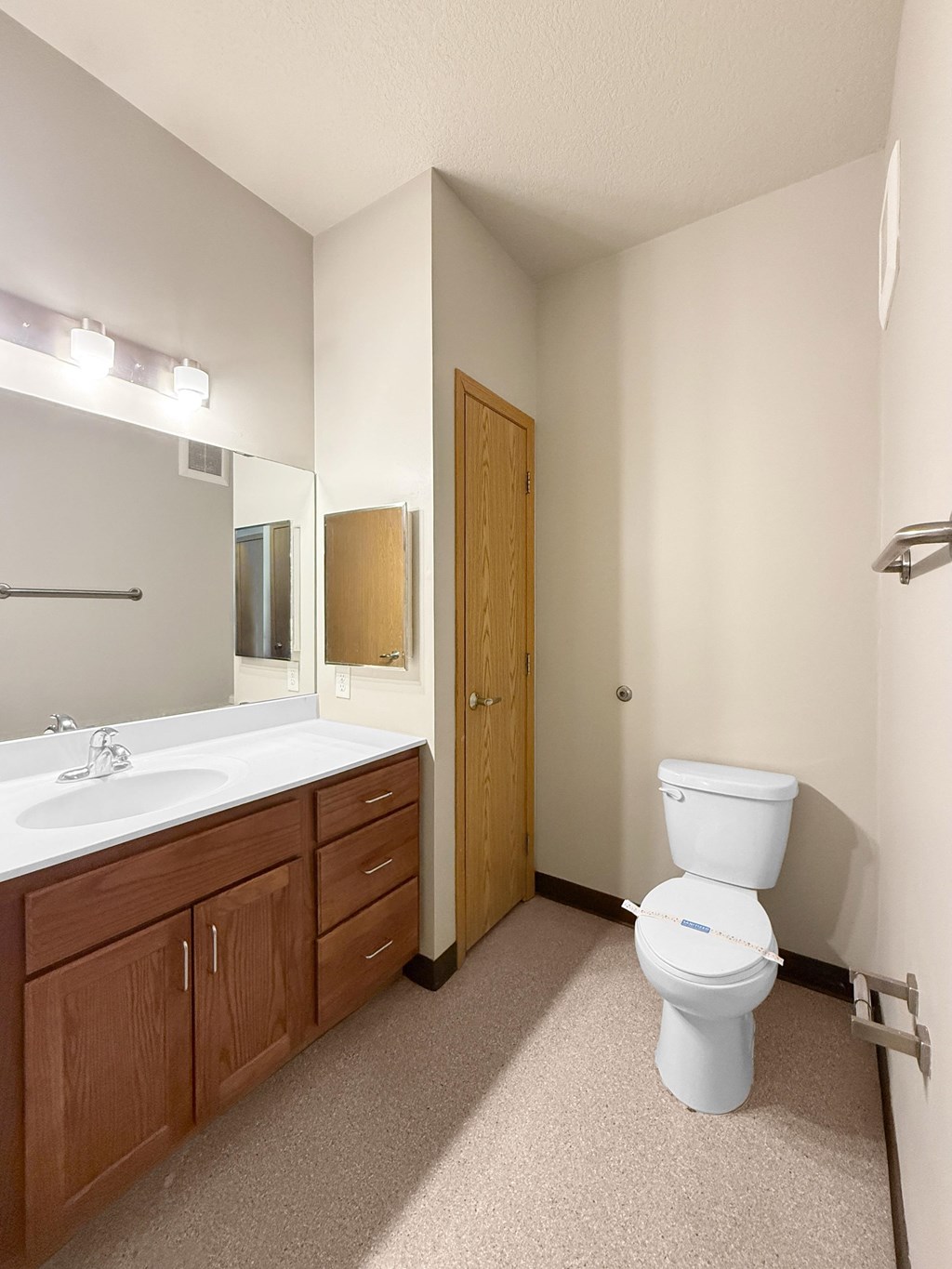 A white toilet sits in a bathroom next to a sink and mirror.