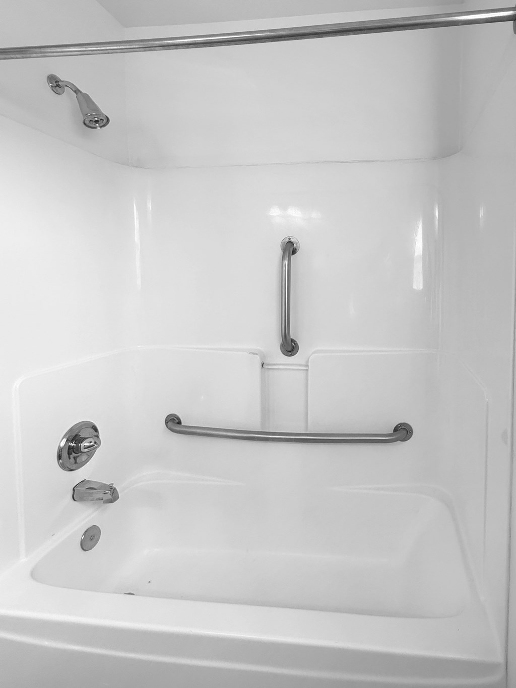 A white bathtub with a shower head and hand held shower.