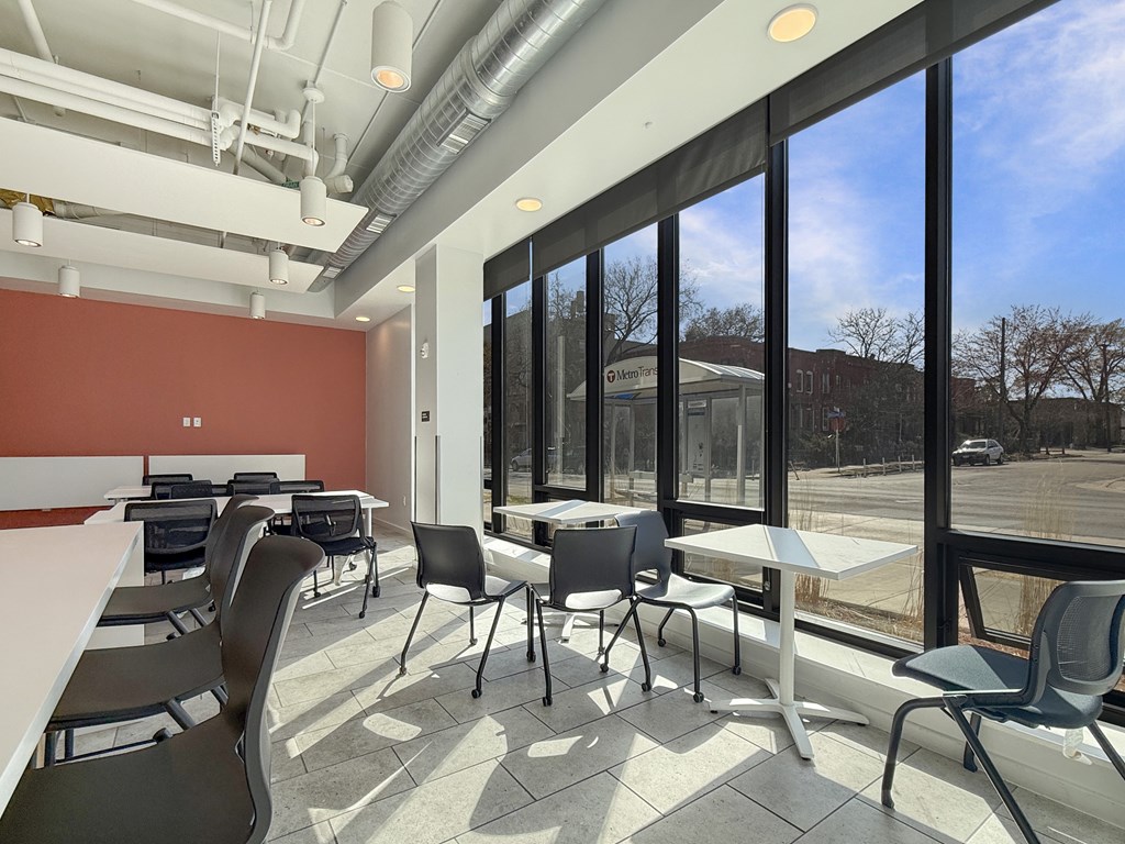 A room with tables and chairs and a window overlooking a parking lot.
