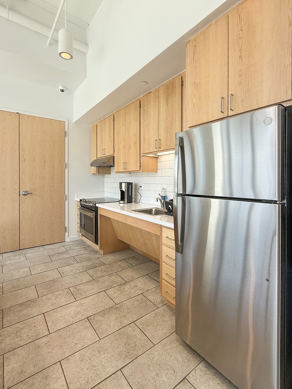 A kitchen with a stainless steel refrigerator and wooden cabinets.