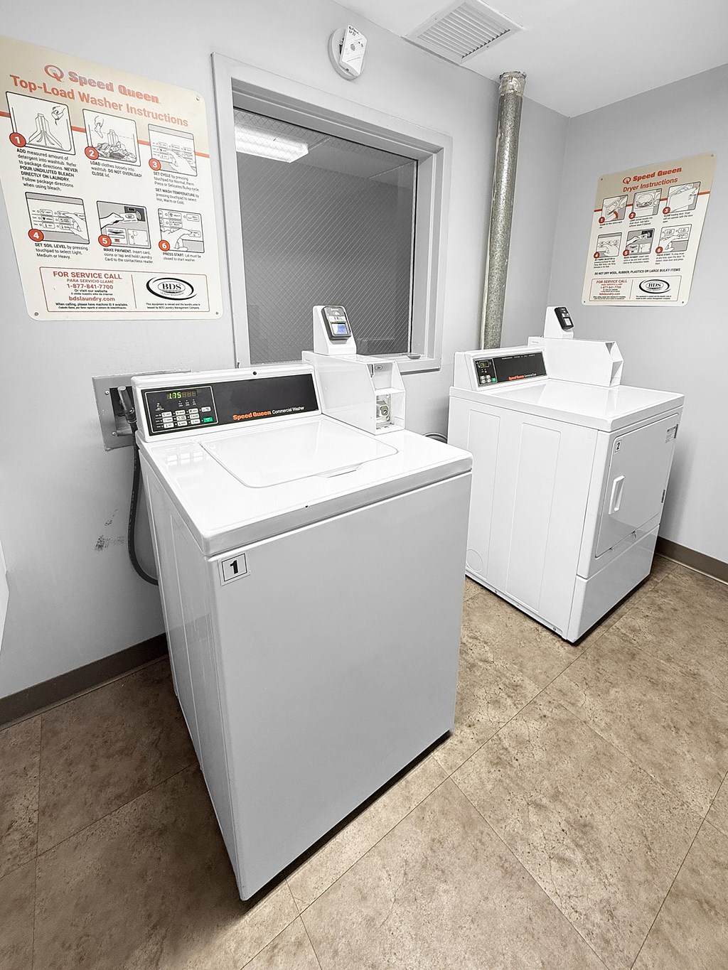 Two washing machines in a laundromat with instructions on the wall.