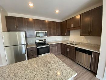 A kitchen with brown cabinets and a granite countertop.