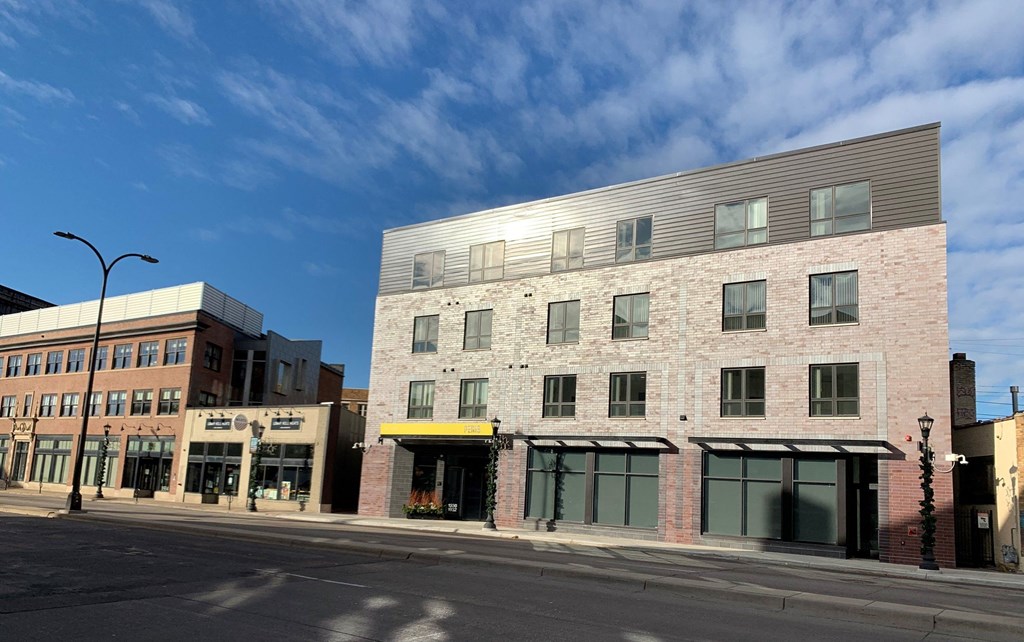 a brick building with a silver roof on a city street