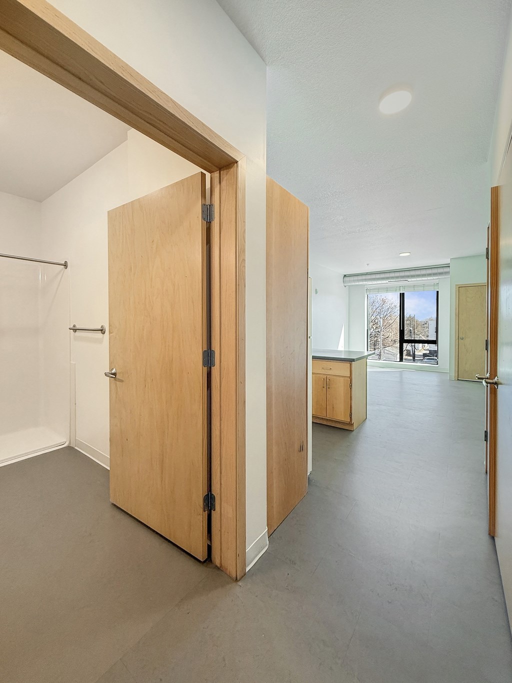 A room with a large wooden door and a grey floor.