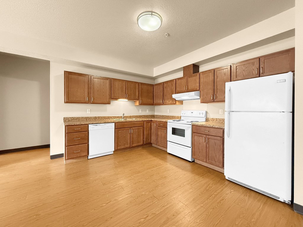 A kitchen with white appliances and wooden cabinets.