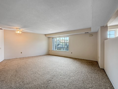 A sparsely furnished room with a carpeted floor and a window.