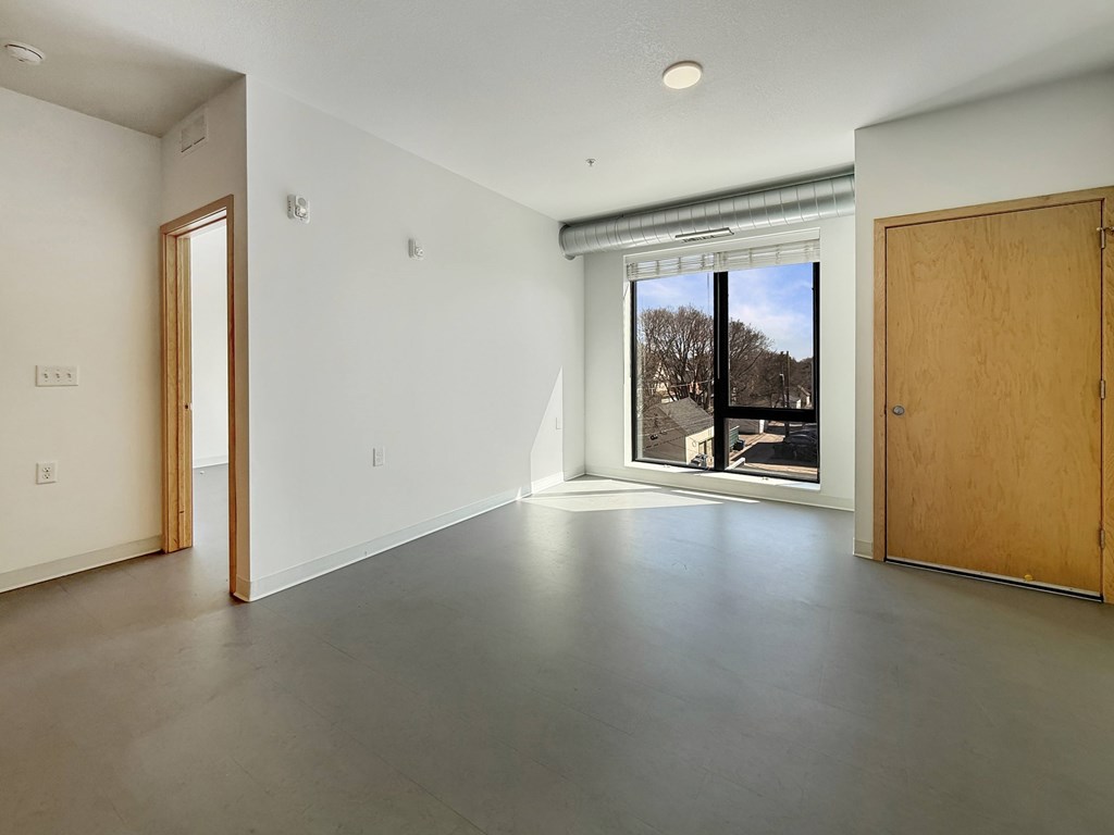A large empty room with a view of the outside through a window.
