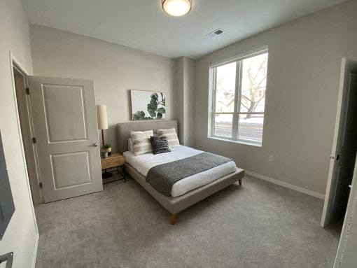 A bedroom with a bed, nightstand, and window.
