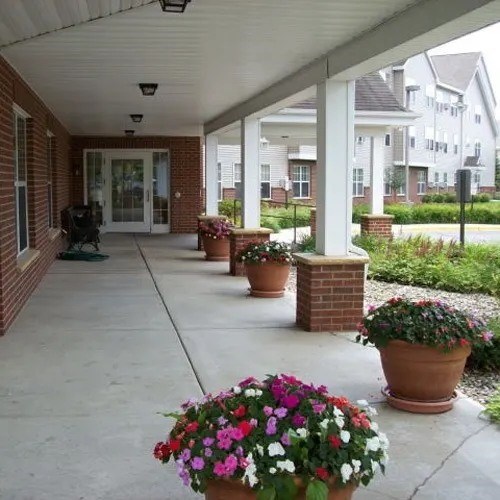 A porch with a brick wall and a white roof with flower pots on it.