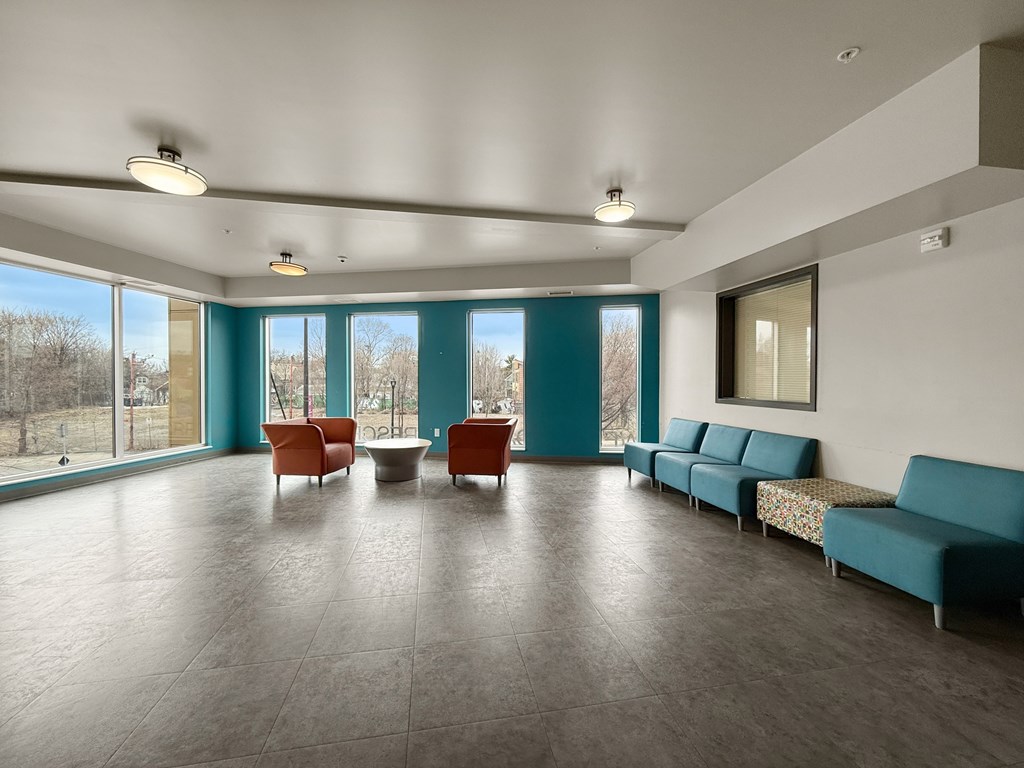 A spacious community lobby with a long couch and a table with chairs.