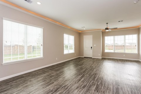 A spacious room with wood flooring and a ceiling fan.