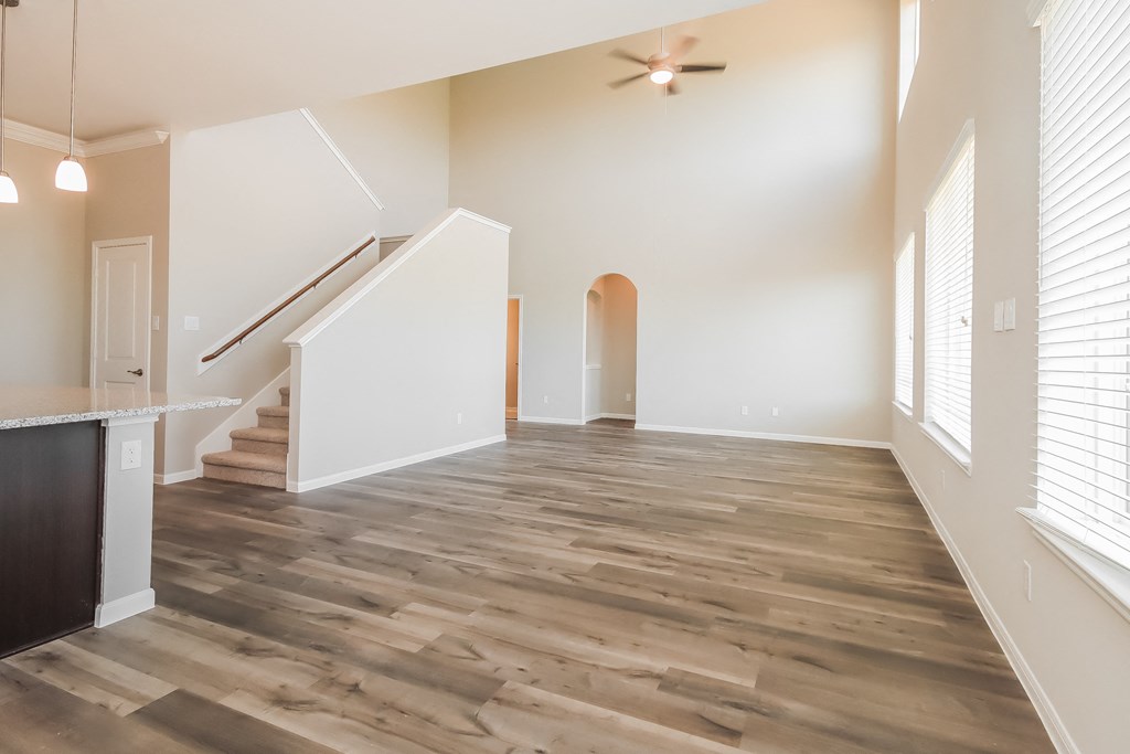 an empty living room with hardwood flooring and a staircase