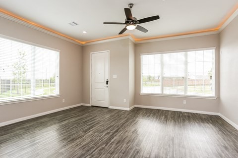 A room with a ceiling fan and wood flooring.