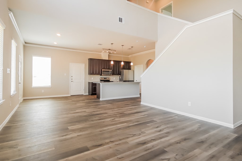 an empty living room and kitchen with wood flooring