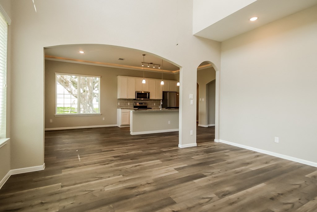 an empty living room with a kitchen and a large window