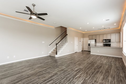 A spacious room with a staircase and a ceiling fan.